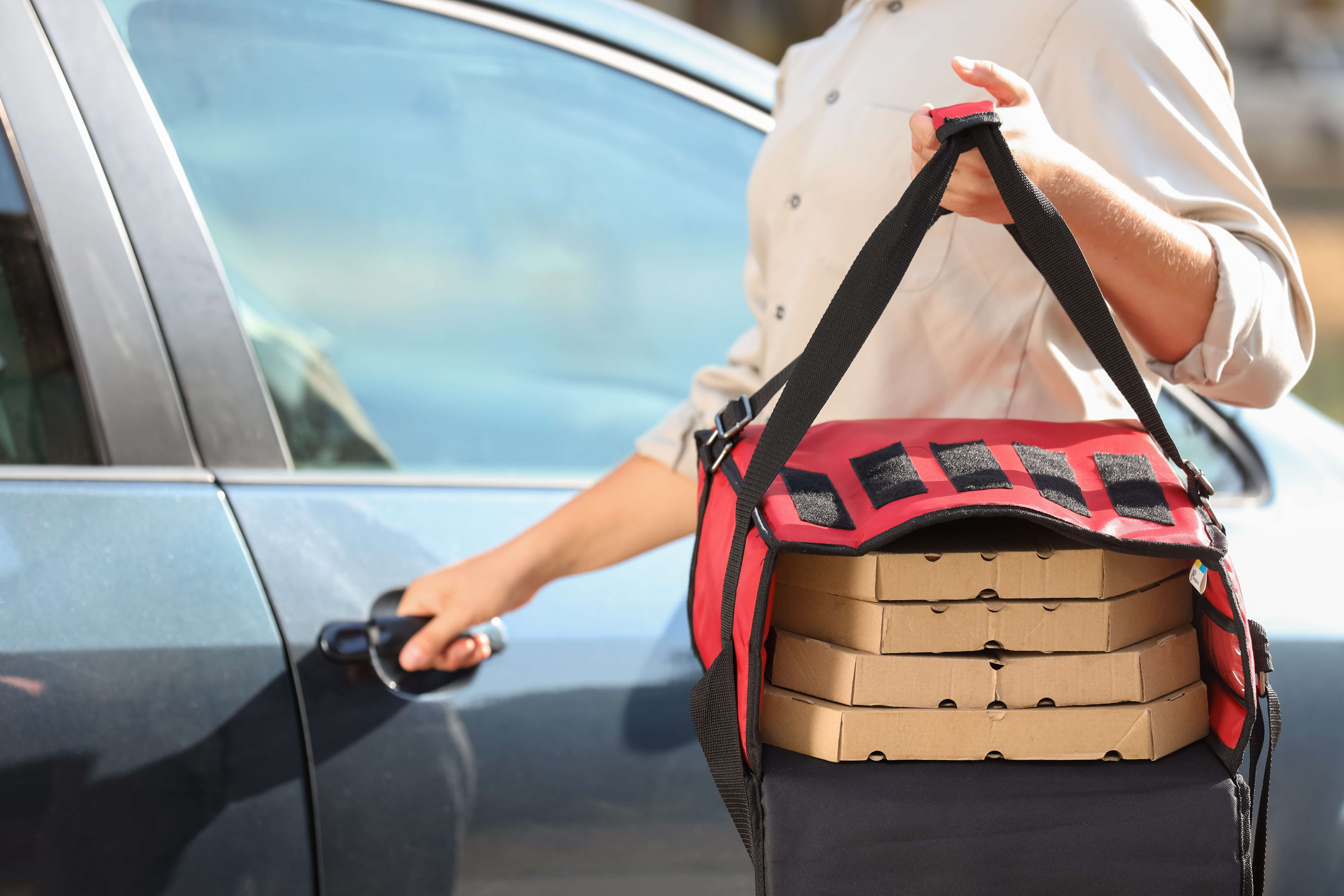 Bezorger die pizza's bezorgt met zijn bedrijfsauto. Kosten van een zakelijke autoverzekering zijn het duurst in deze sector.